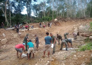 Personel Satgas TMMD Ke-119 Manfaatkan Batu-Batu yang Ada di Sekitaran Lokasi untuk Penimbunan Jalan yang Berlumpur